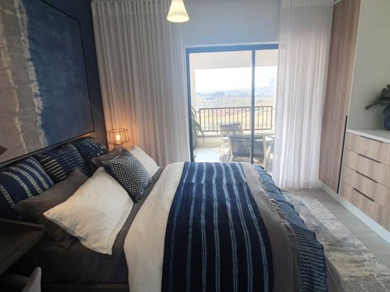 A well-appointed bedroom featuring built-in cupboards, tiled flooring, and a sliding glass door providing direct access to a private balcony.