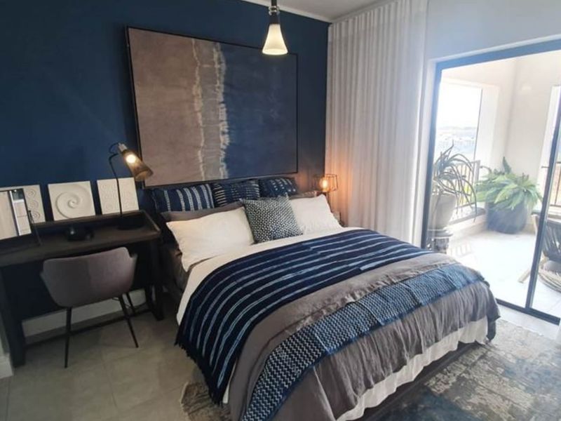 A well-appointed bedroom featuring tiled flooring, modern pendant lighting, and a large sliding glass door providing direct access to a private balcony.