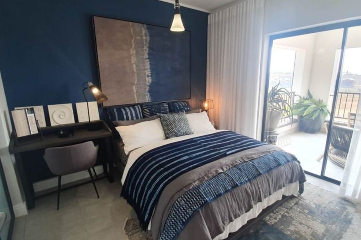 A well-appointed bedroom featuring tiled flooring, modern pendant lighting, and a large sliding glass door providing direct access to a private balcony.