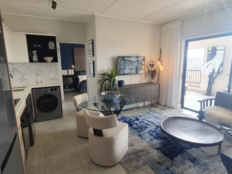 Modern open-plan living area featuring a compact kitchen with marble-look finishes, tiled floors, and seamless access to a private balcony.