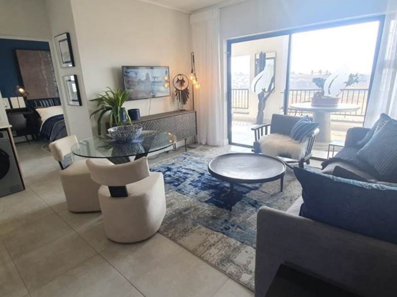 Modern open-plan living area featuring tiled floors, integrated kitchen cabinetry, and large sliding doors leading to a private balcony.