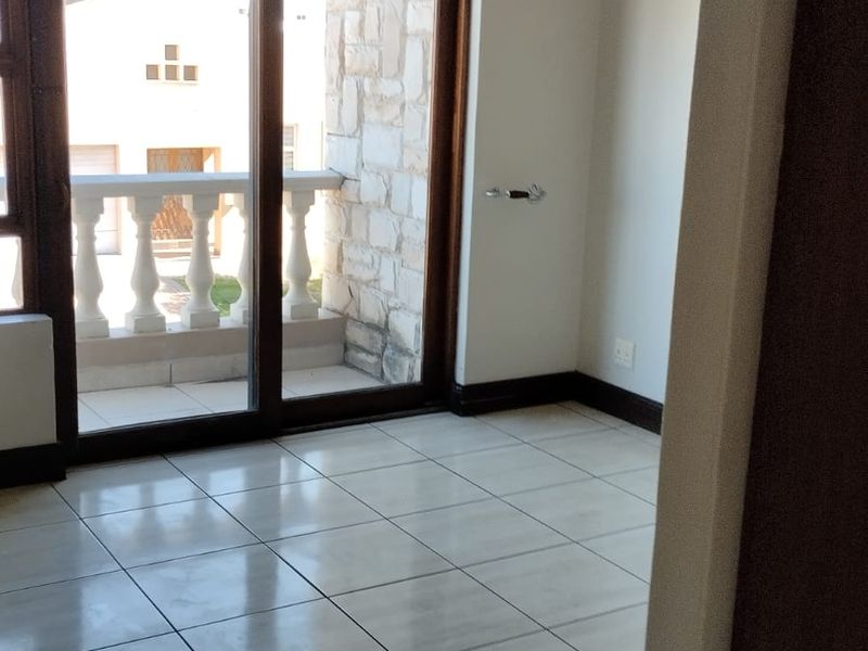 An empty bedroom featuring tiled flooring, neutral walls, and a sliding glass door providing direct access to a private balcony.