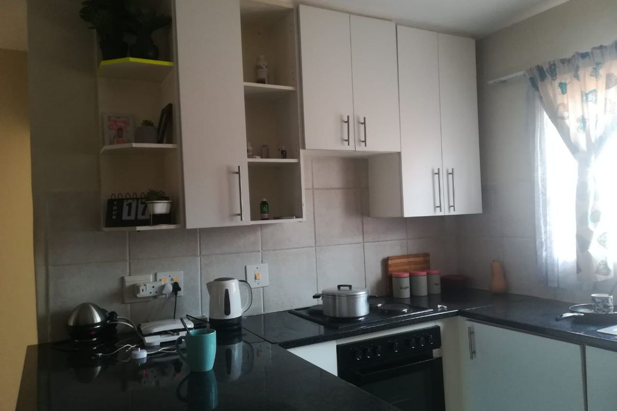 A functional kitchen featuring white built-in cabinetry, dark granite countertops, and a built-in electric oven and hob with tiled backsplash.
