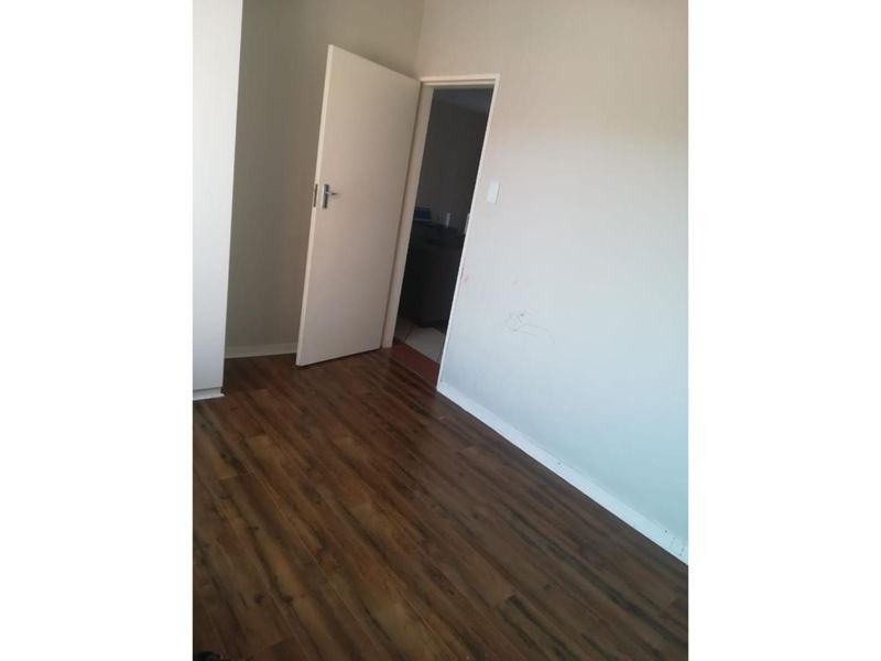 An empty bedroom featuring dark laminate flooring and neutral wall finishes, ready for personalization.