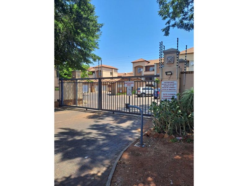 Secure gated entrance to the apartment complex featuring automated access control, perimeter walling, and electric fencing for enhanced security.