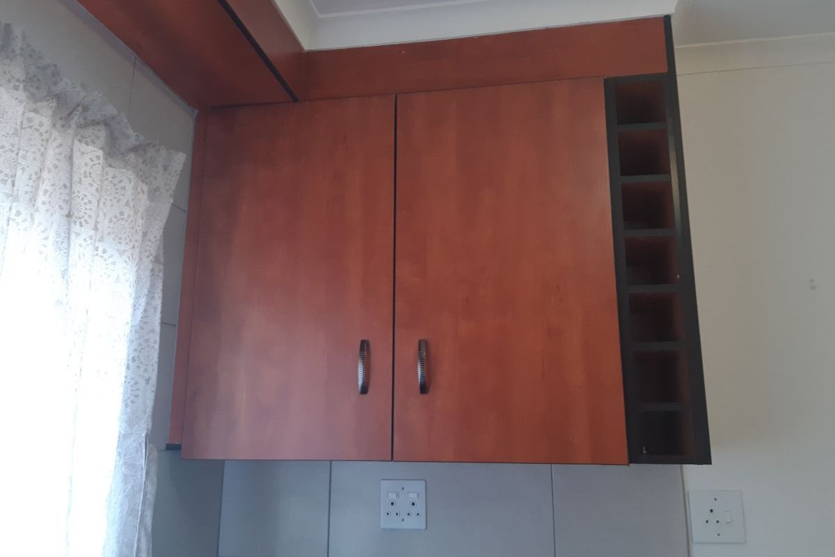 A close-up view of kitchen wall-mounted cabinetry featuring a built-in wine rack and tiled backsplash.
