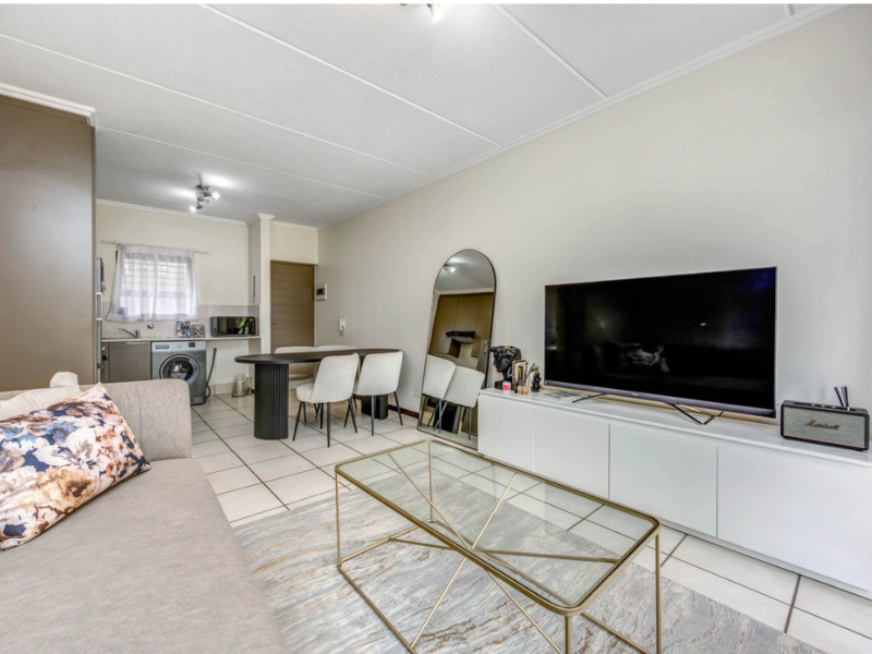Open plan living area featuring tiled flooring and an integrated kitchen space with built-in cabinetry and sink.