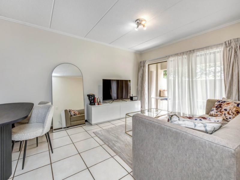 Bright open-plan living area featuring tiled flooring and a sliding glass door providing access to the patio.