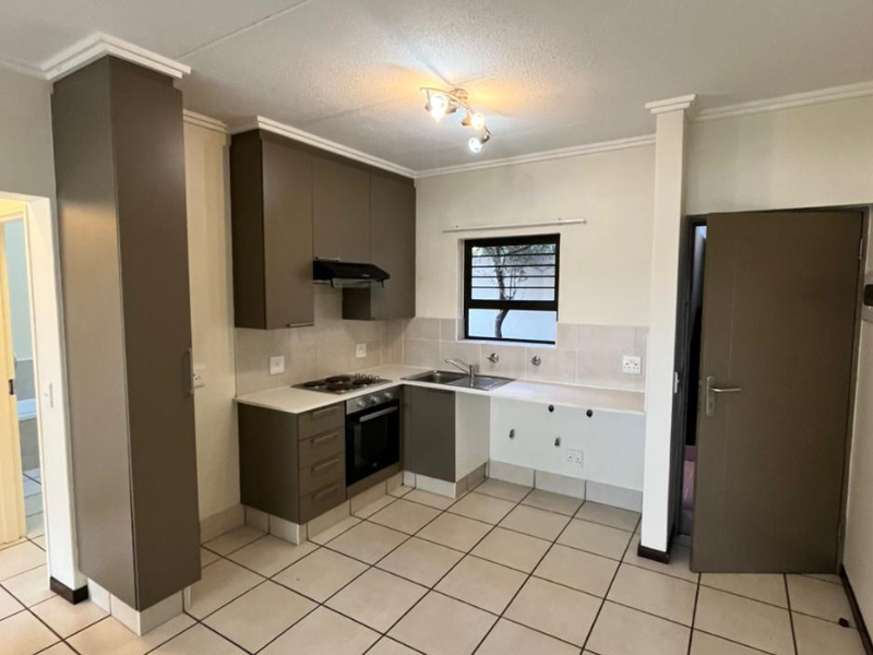 A functional kitchen featuring built-in cabinetry, an electric hob, oven, extractor fan, and tiled flooring. The space is currently vacant and ready for updates.