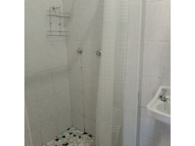 A compact bathroom featuring a tiled shower enclosure with a mosaic floor and a wall-mounted basin.