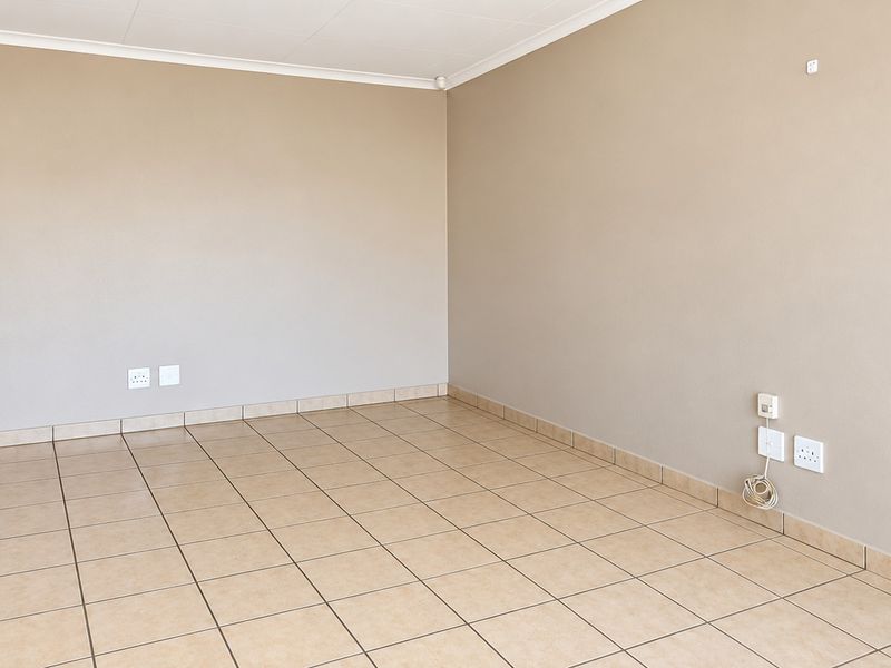 A bright, empty living room featuring neutral walls, ceramic tile flooring, and coved ceilings, providing a clean and versatile space ready for personalization.