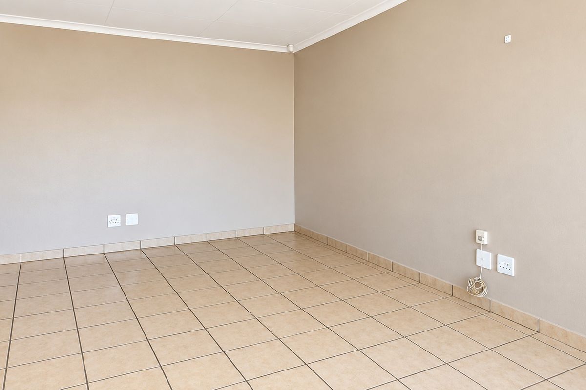 A bright, empty living room featuring neutral walls, ceramic tile flooring, and coved ceilings, providing a clean and versatile space ready for personalization.