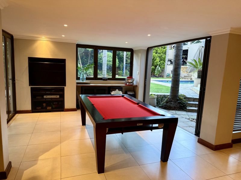 Spacious living area featuring tiled floors, recessed lighting, and large bi-fold doors that open directly onto the outdoor pool and garden area.