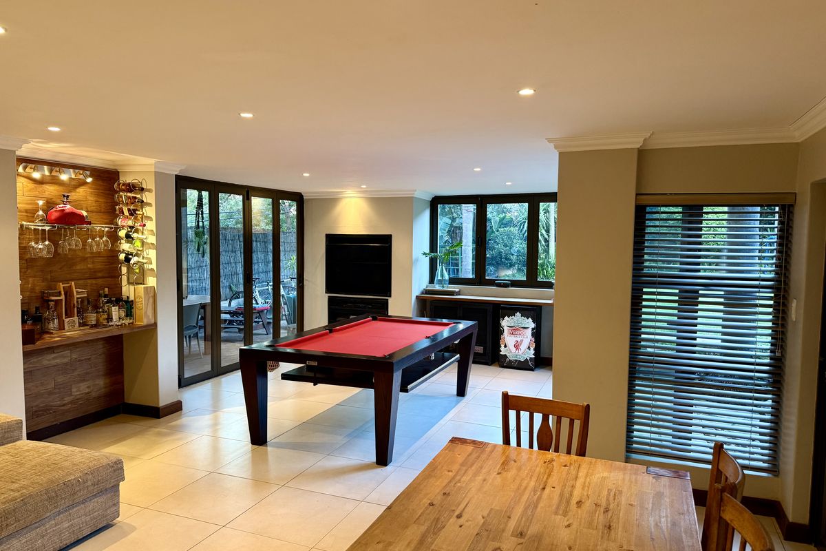 Spacious living area featuring tiled floors, recessed lighting, a built-in bar, and large aluminium sliding doors providing access to the outdoor patio.