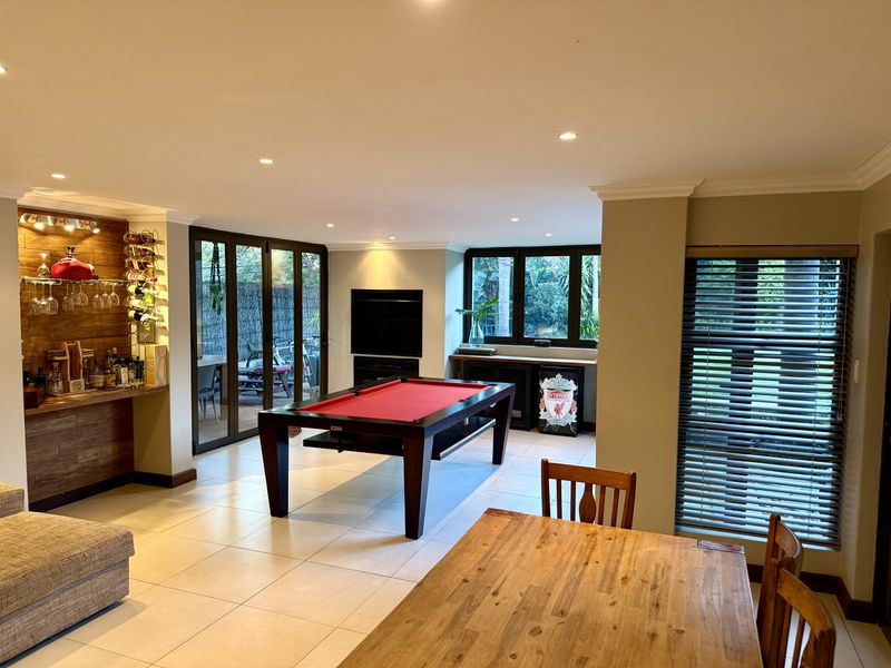 Spacious living area featuring tiled floors, recessed lighting, a built-in bar, and large aluminium sliding doors providing access to the outdoor patio.