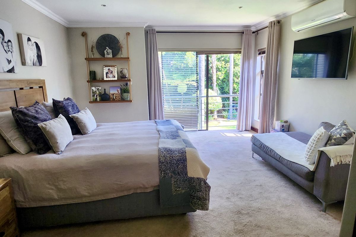 Spacious bedroom featuring carpeted flooring, wall-mounted air conditioning, and a sliding glass door providing access to an outdoor area.