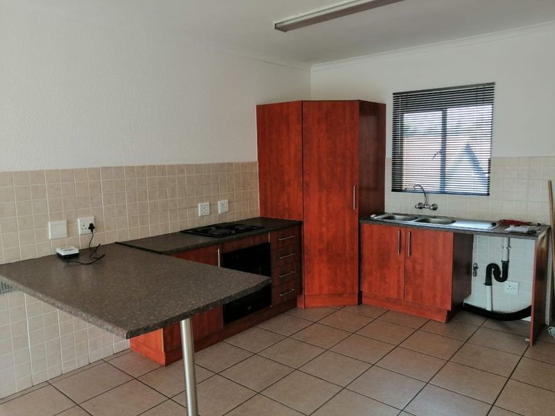 A functional kitchen featuring wood-finish cabinetry, laminate countertops, built-in oven and hob, tiled backsplash, and tiled flooring. Requires minor repairs to cabinetry.