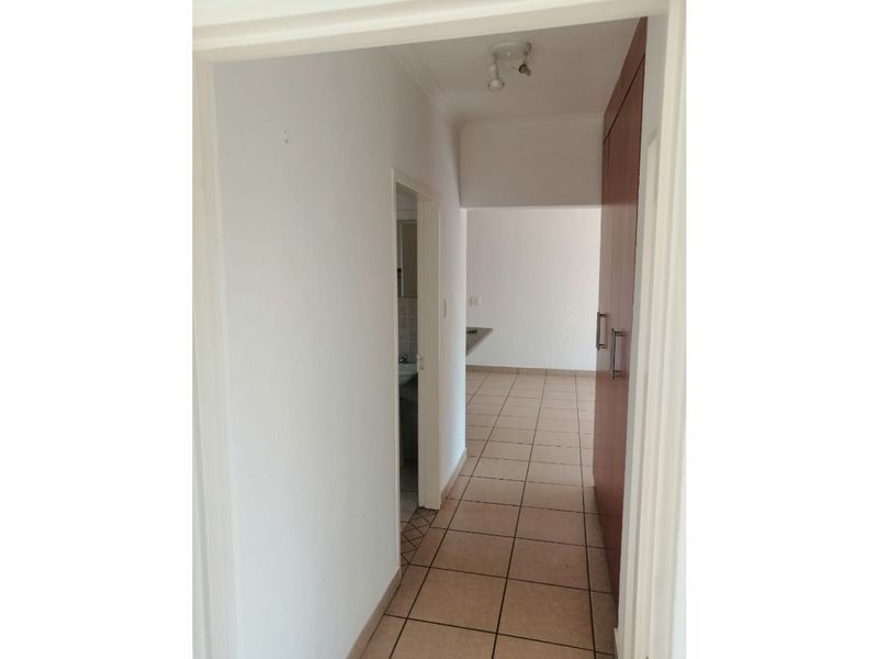 A functional hallway featuring tiled flooring and built-in storage cupboards, providing access to adjacent rooms within the townhouse.