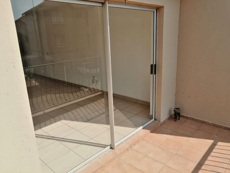 A compact balcony area featuring tiled flooring, a sliding glass door entrance, and a metal balustrade, offering a functional outdoor space.