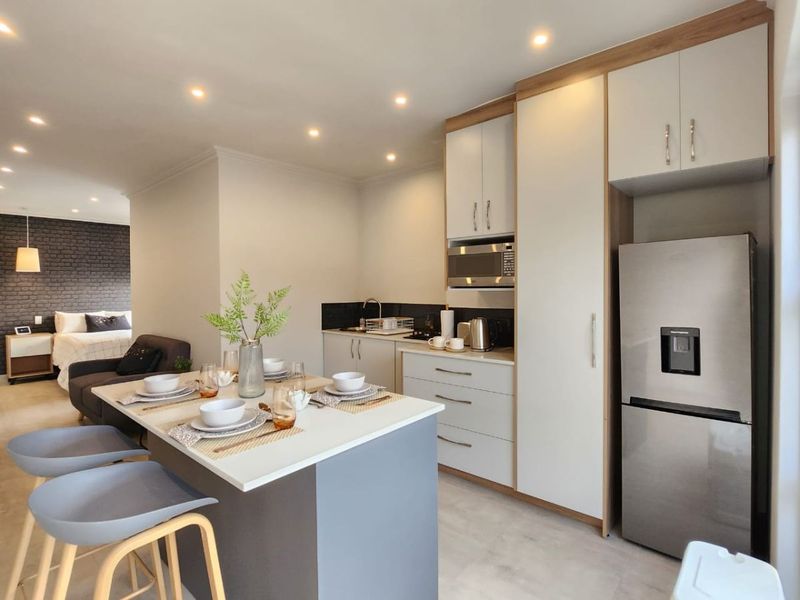 Modern open-plan kitchen featuring sleek cabinetry, integrated microwave, and a central breakfast island, seamlessly flowing into the adjacent living and bedroom area.