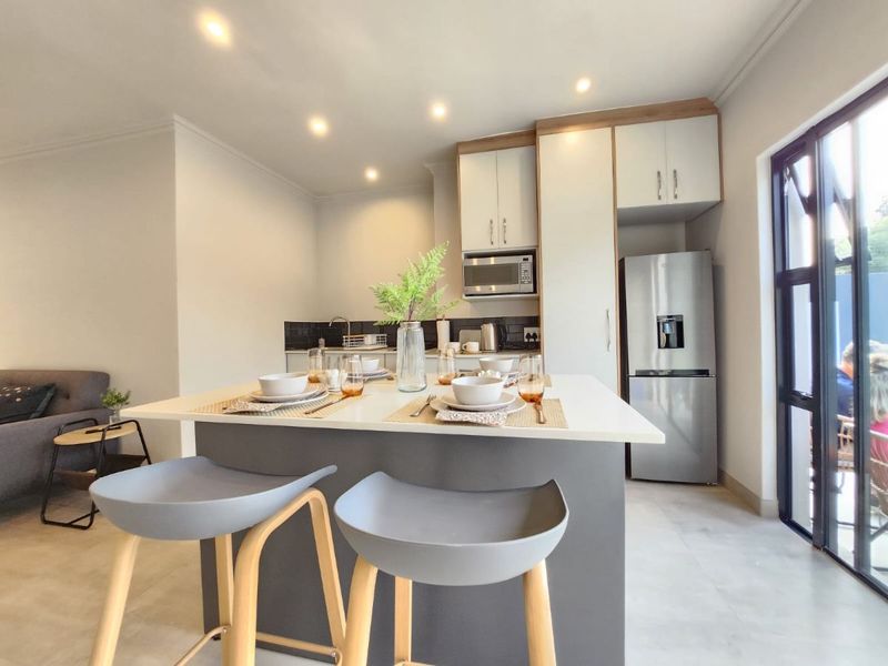 Modern open-plan kitchen featuring a central island with breakfast bar seating, sleek cabinetry, and integrated appliances, seamlessly flowing into the living area.