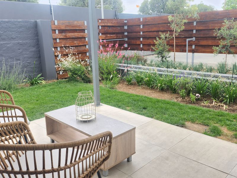 A private outdoor patio area featuring tiled flooring, a well-maintained lawn, and timber privacy screening.