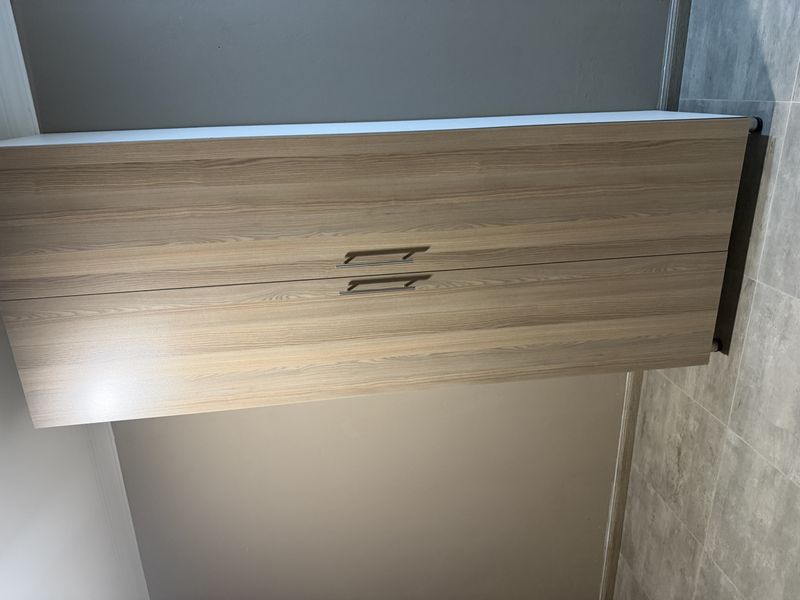 A clean, empty bedroom space featuring modern wood-finish built-in wardrobes and neutral tiled flooring.