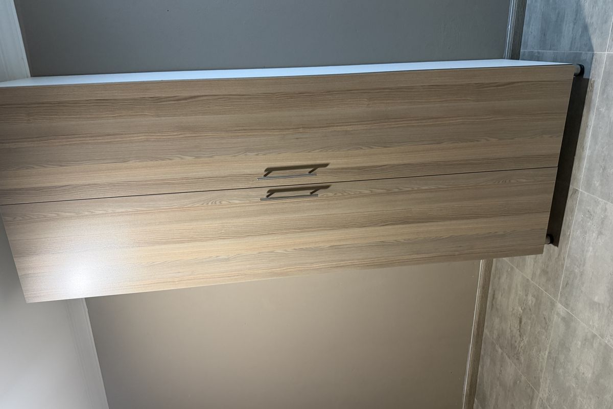 A clean, empty bedroom space featuring modern wood-finish built-in wardrobes and neutral tiled flooring.