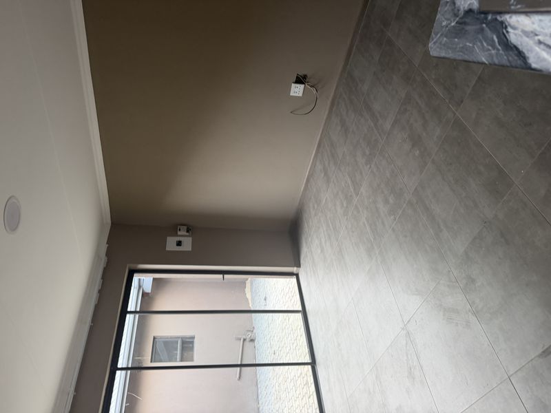An empty living room featuring large sliding glass doors leading to an outdoor area, tiled flooring, and recessed lighting.