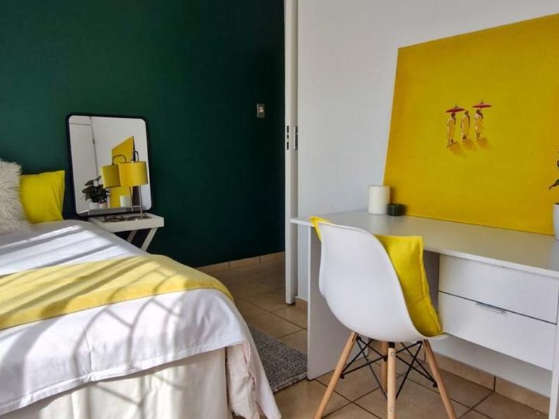 A bright bedroom featuring tiled flooring and a bold green accent wall, providing a clean and modern living space.
