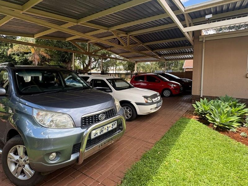 A spacious covered carport area with paved flooring, providing ample sheltered parking space for multiple vehicles.