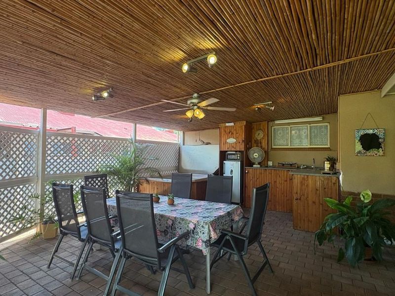 Covered outdoor patio featuring a bamboo ceiling, built-in cabinetry with a sink, and paved flooring, ideal for alfresco dining and entertaining.