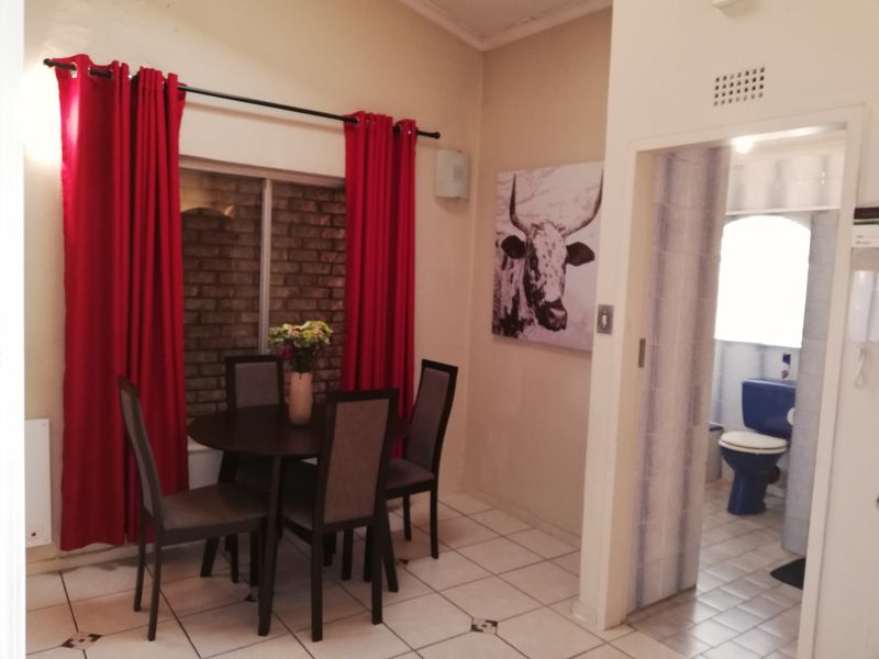 Dining area featuring tiled flooring and an exposed brick feature wall, with direct access to an adjacent bathroom.