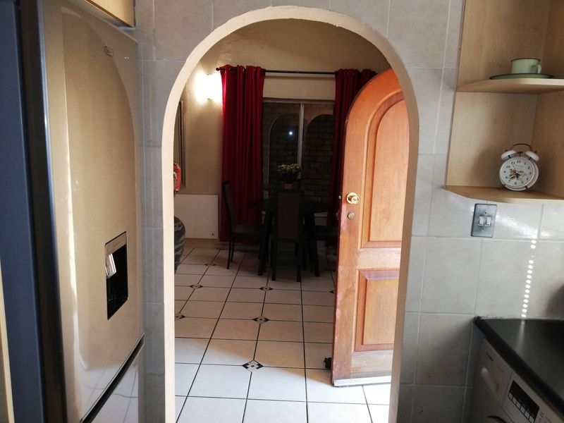 A view from the kitchen through an arched doorway into an adjacent dining area featuring tiled floors and neutral wall finishes.