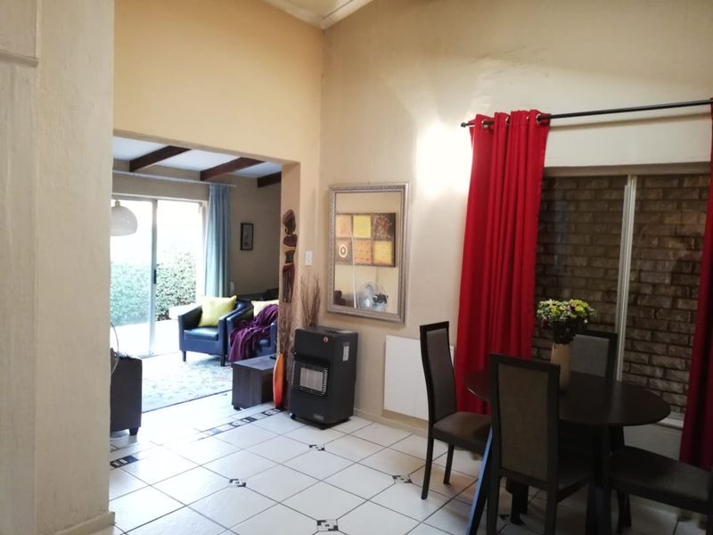 Open-plan living and dining area featuring tiled floors, exposed brickwork, and sliding glass doors leading to an outdoor space.