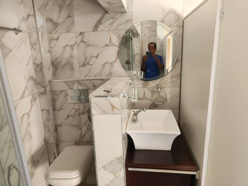 Modern bathroom featuring marble-effect wall tiles, a wall-mounted toilet with concealed cistern, and a vessel sink vanity.