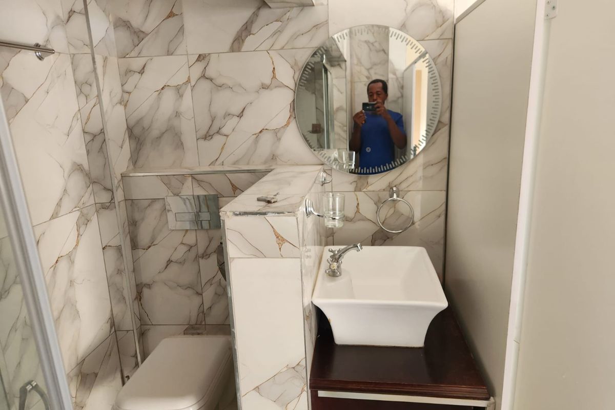 Modern bathroom featuring marble-effect wall tiles, a wall-mounted toilet with concealed cistern, and a vessel sink vanity.