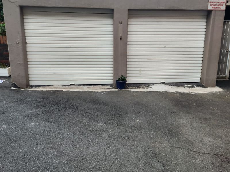 A double garage featuring white roller shutter doors and a paved driveway area.
