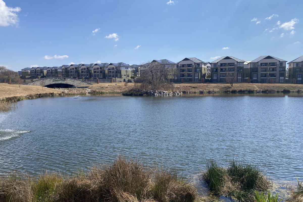 A scenic view of the estate lake, featuring a stone bridge and surrounding residential apartment buildings.