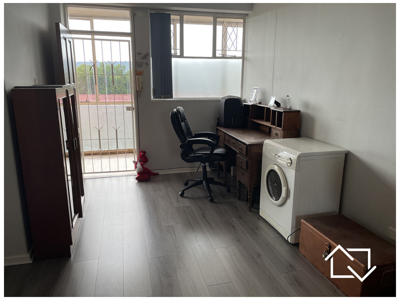 A functional utility space featuring modern laminate flooring, large windows for natural light, and direct access to an outdoor balcony area.