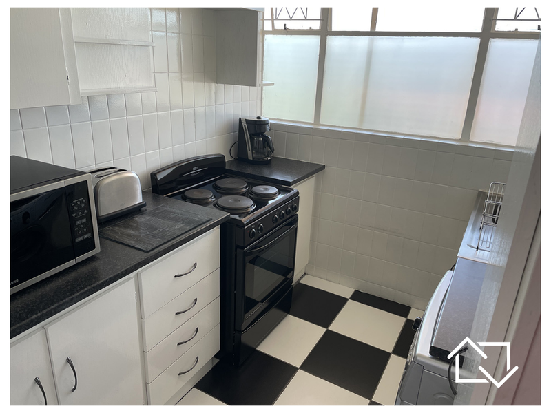 Compact kitchen featuring tiled splashbacks, laminate countertops, and a freestanding electric stove, with classic black and white checkered flooring.