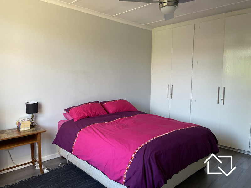 A bedroom featuring laminate flooring, a ceiling fan, and ample built-in cupboard storage space.