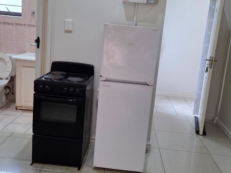 Kitchen area featuring tiled flooring and an adjacent bathroom with dated fixtures, requiring cosmetic updates to improve the overall aesthetic and functionality.