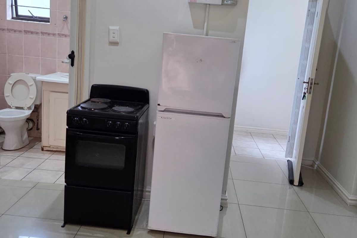 Kitchen area featuring tiled flooring and an adjacent bathroom with dated fixtures, requiring cosmetic updates to improve the overall aesthetic and functionality.