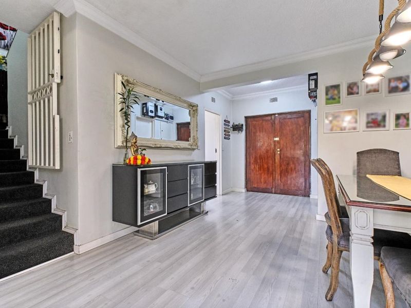 Welcoming entrance hall featuring laminate flooring, a staircase with a security gate, and double wooden front doors leading into the home.