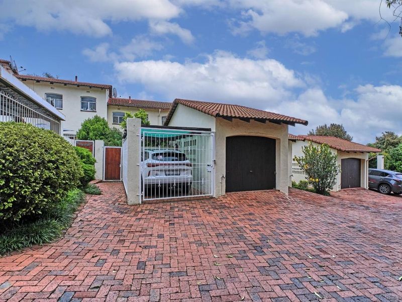 Front exterior view of the cluster property featuring a brick paved driveway, a garage, and a covered carport area.