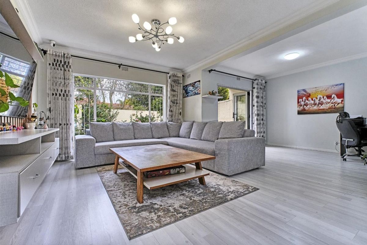 Spacious living room featuring light-toned laminate flooring, large windows for natural light, and direct access to the outdoor area.