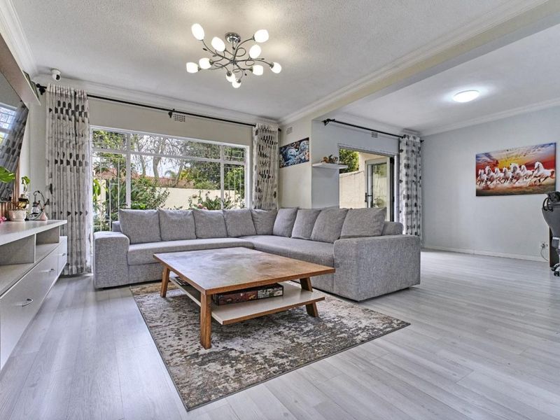 Spacious living room featuring light-toned laminate flooring, large windows for natural light, and direct access to the outdoor area.