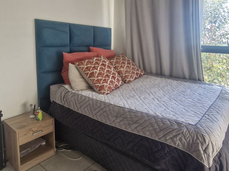 A bedroom featuring tiled flooring and a large window allowing natural light, providing a functional space for rest.