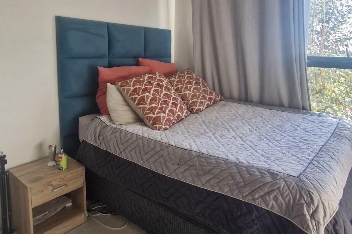 A bedroom featuring tiled flooring and a large window allowing natural light, providing a functional space for rest.